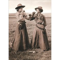 two women in long skirts and hats are talking