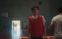 a young man standing in front of a basketball hoop with his head turned to the side