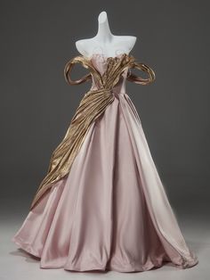 a pink and gold dress on display in front of a mannequin's head