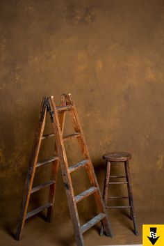 an old wooden ladder leaning against a brown wall next to a stool with a sign on it