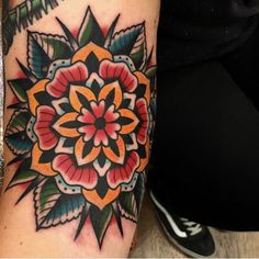 a woman's arm with a colorful flower tattoo on the left side of her leg