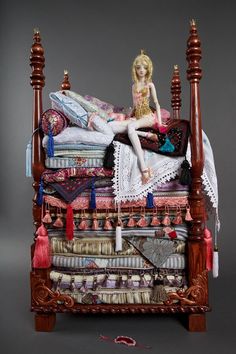 a doll sitting on top of a bed made out of books