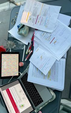 an open laptop computer sitting on top of a desk next to papers and other items