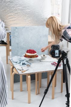 a woman taking a photo of a cake on a table with a video camera in front of her