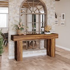 a wooden table sitting in the middle of a living room next to a brick wall