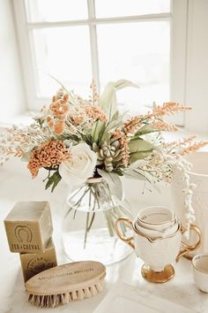 a vase filled with lots of flowers next to a cup and saucer on a table