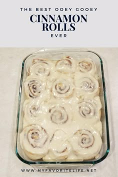 a glass dish filled with cinnamon rolls on top of a white counter next to a pink sign