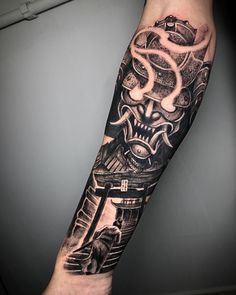 a man's arm with a black and white tattoo design on the left forearm