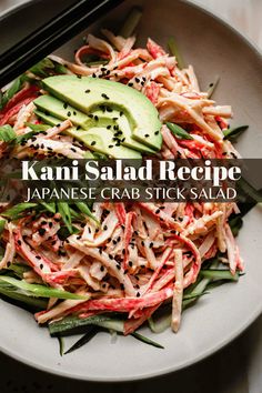 a white plate topped with salad next to chopsticks