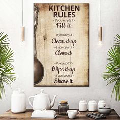 a kitchen rules poster on the wall above a table with teapots and cups