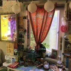 a cluttered room with many items on the table and hanging from the ceiling above it