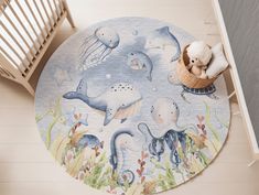 a child's rug with sea animals and marine creatures on the floor next to a crib