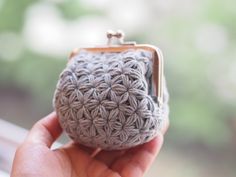 a small crocheted purse is held in someone's hand with the clasp closed