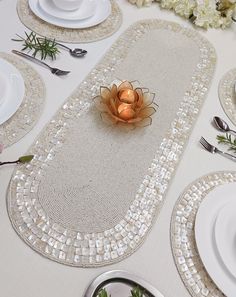 the table is set with white plates and silver utensils, including an orange flower