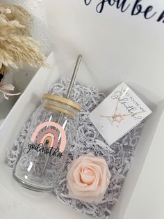 a pink rose sitting on top of a table next to a card in a box