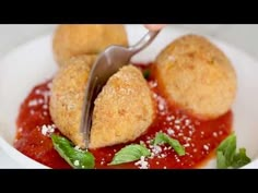 a person is cutting into some food in a white bowl with sauce and parmesan sprinkles