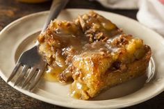 a white plate topped with two pieces of cake covered in caramel sauce next to a fork