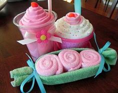 some towels and cups on a table with a pink cupcake in the middle one