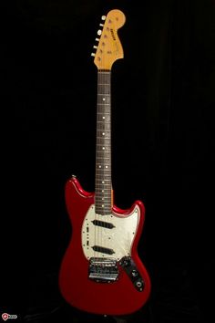 a red electric guitar sitting on top of a black background