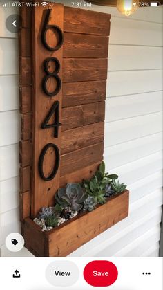 a wooden house number sign with succulents and plants in the planter