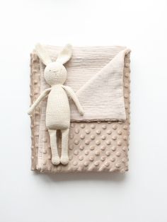 a knitted bunny doll laying on top of a blanket with polka dot patterning