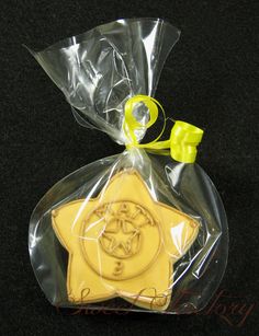 a star shaped cookie wrapped in plastic on a black tablecloth with yellow ribbon around it