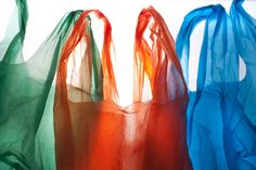 three bags are lined up with different colored organes hanging from the top one is blue, green and orange