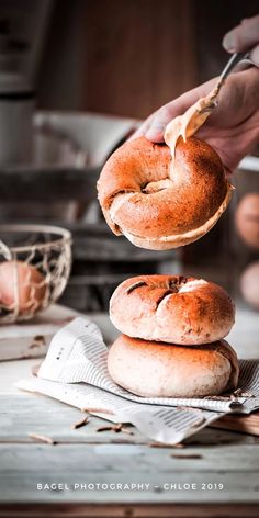 a person is holding a bagel in their hand and it's on top of another bagel