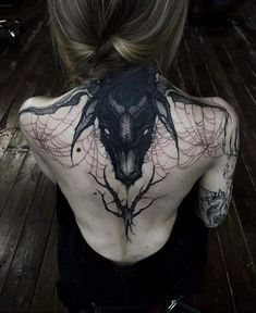 the back of a woman's body with tattoos on it and an animal head