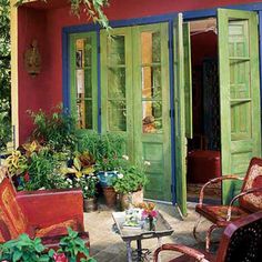 an outdoor patio with green doors and potted plants