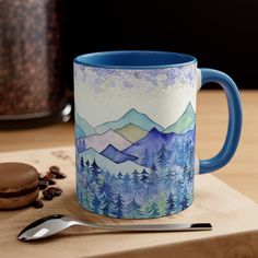 a blue coffee mug sitting on top of a wooden cutting board next to a cookie