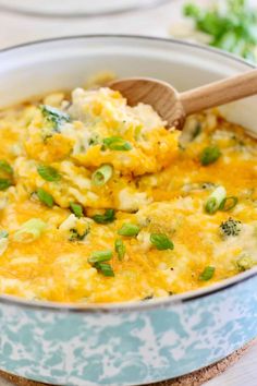 a casserole with broccoli and cheese in a blue dish on a wooden spoon