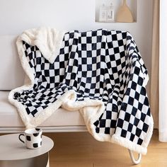 a black and white checkered blanket sitting on top of a couch next to a cup