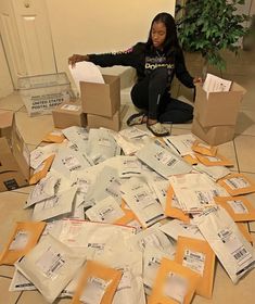 a woman sitting on the floor surrounded by boxes and mail bags that are all over the floor