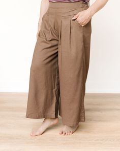 These pants are wide-legged and high-waisted, made from a flowy, lightweight fabric in a neutral, earthy brown shade. They have a relaxed fit, which makes them ideal for a comfortable yet stylish look. The waistband appears slightly structured, possibly elasticated at the back for extra comfort, and features a unique V-shaped design at the front, adding a bit of flair to the otherwise simple cut. The wide legs give the pants an airy, loose silhouette, perfect for casual or semi-dressy occasions. These pants can easily be paired with a variety of tops for a chic, effortless outfit. Non-stretch Brown Wide Leg Pants With Pockets, Brown Wide Leg Ankle-length Pants With Pockets, Brown Ankle-length Wide Leg Pants With Pockets, Brown Baggy Wide Leg Pants For Work, Brown Wide Leg Pants With Pockets, High-waisted Brown Harem Pants For Spring, Brown High-waisted Harem Pants For Spring, Baggy Brown Ankle Pants, Brown Relaxed Fit Harem Pants For Spring