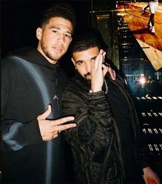 two men standing next to each other in front of a cityscape at night