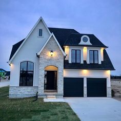 a white and black house with two garages in the front yard at night time