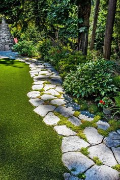 a stone path in the middle of a lush green yard