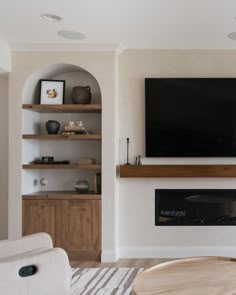 a flat screen tv mounted on the wall above a fireplace in a living room with built - in shelving