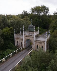 an aerial view of a bridge and building in the middle of some trees with a road going through it