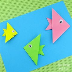 two fish made out of paper sitting on top of a blue sheet with green polka dots