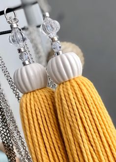 yellow and white earrings hanging from chains with crystal beads on it's ear ends