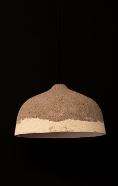 a brown and white light hanging from a ceiling fixture in a dark room with black walls