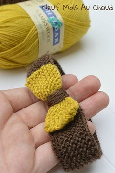 a hand holding a yellow and brown knitted object