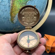 a person holding a compass in their hand with a world map behind them and the words to my grandson on it