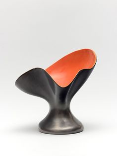 an orange and black chair sitting on top of a white floor