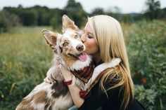 a woman is kissing her dog outside in the grass