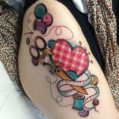 a woman's thigh with scissors and a heart tattoo on the side of her leg