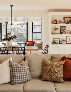 a living room filled with furniture and lots of windows next to a dining room table