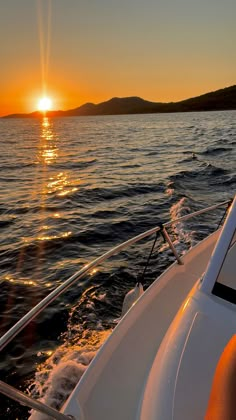 the sun is setting over the water on a boat